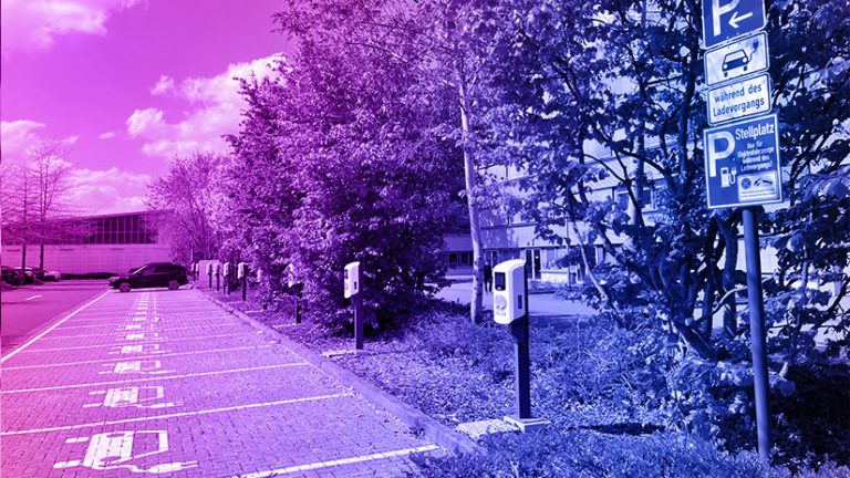 Parkplatz für E-Autos mit TankE Ladesäulen und Bäumen im Hintergrund