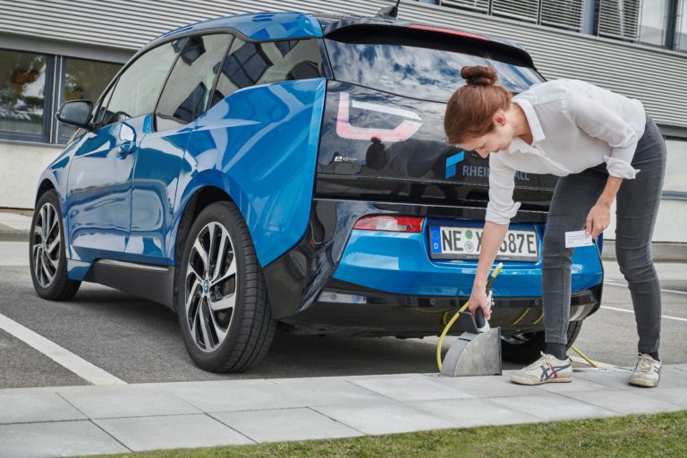 Eine Person steckt ein Ladekabel in einen Ladebordstein